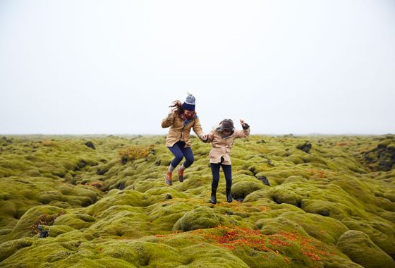 Two friends jumping in a field making Buddhist friends