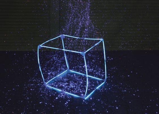 Neon cube with purple flecks surrounding it; present moment buddhist